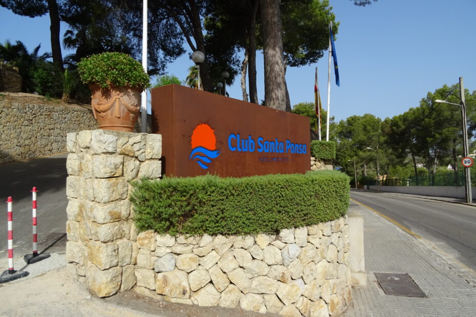 Eingangsschild des Club Santa Ponsa auf Mallorca mit Steinmauer und Bepflanzung