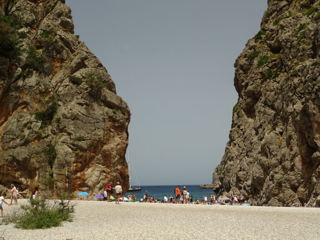Strand im Torrent de Pareis, eingerahmt von hohen Felsen, mit Badegäste