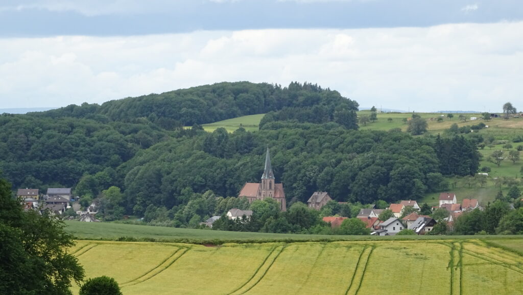 Blick auf Breitenbach mit Kirche, umgeben von Wäldern und Feldern im Sommer