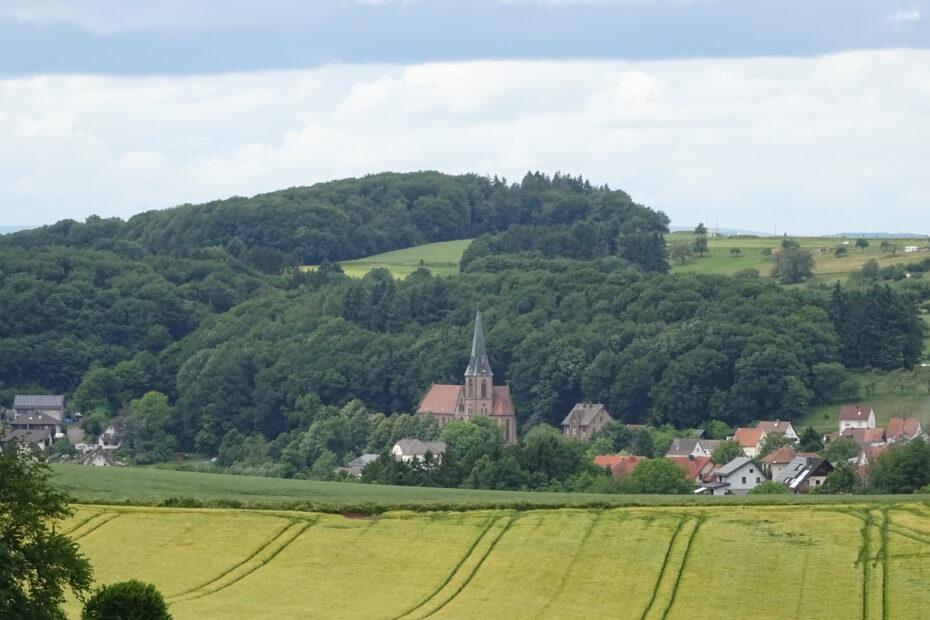 Blick auf Breitenbach mit Kirche, umgeben von Wäldern und Feldern im Sommer