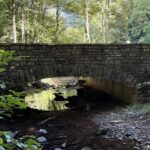 Das Züscht – Natursteinbrücke über einen Bach im Wald bei Züsch